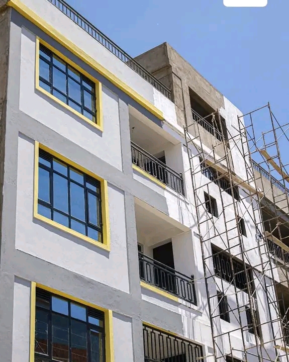 A commercial buildiing exterior painting in progress with white,
             grey and yellow color combinations
