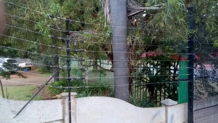 An Electric fence extending high above a short wall fence
