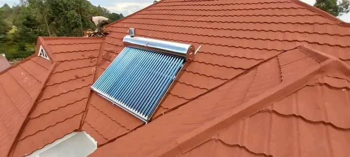 A Solar Water heater being installed by an electrician on an orange roof in Juba, South Sudan