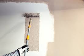 A hand holding a painting brush and painting a wall in Juba, South Sudan