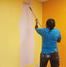 A female painter with a paint roller in hand painting in Juba, South Sudan