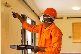 A male painter with a paint roller in hand painting in Juba, South Sudan