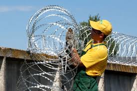 A technician fixing razor wire on top of a wall fence in Juba, South Sudan.